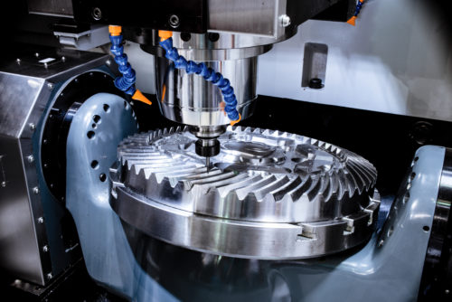 A modern CNC milling machine makes a large cogwheel. Accurate metal working. Shooting in real conditions, maybe some blurring and grain.